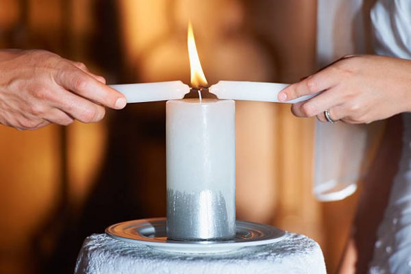 Cropped closeup shot of a couple lighting candles during their wedding ceremony